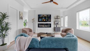 Un salon moderne avec une cheminée, deux canapés, une table basse et un téléviseur fixé au mur.
