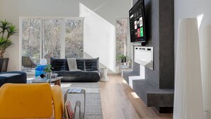 Ein modernes Wohnzimmer mit einem schwarzen Ledersofa, einem gelben Sessel, einem Couchtisch und einem flachbildfernseher an einer grauen Wand.
