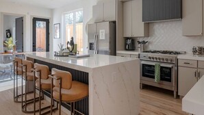 Eine moderne Küche mit einer großen Kochinsel, Barhocker, einem Herd und einem Kühlschrank.