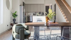 Eine moderne Küche mit grauen Schränken, ein Essbereich mit einem Holztisch und eine Treppe.