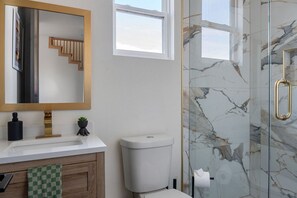 A bathroom with a marble shower, a toilet, a sink with a mirror, and a window. - Ultra-Spacious Boutique Retreat in Downtown Dallas (Dallas)