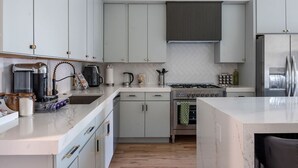 Een moderne keuken met witte kastjes, een roestvrijstalen koelkast, een gasfornuis en een vaatwasser.