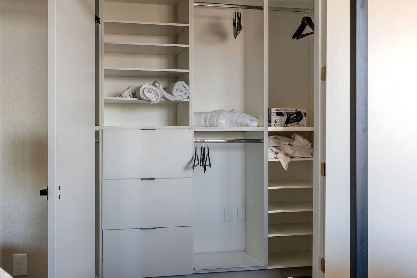 A walk-in closet with multiple shelves, hanging space, and a folded clothes rack.