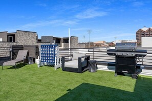 Eine Dachterrasse mit Grill, Sitzgelegenheiten und einer blauen Wasserspende.