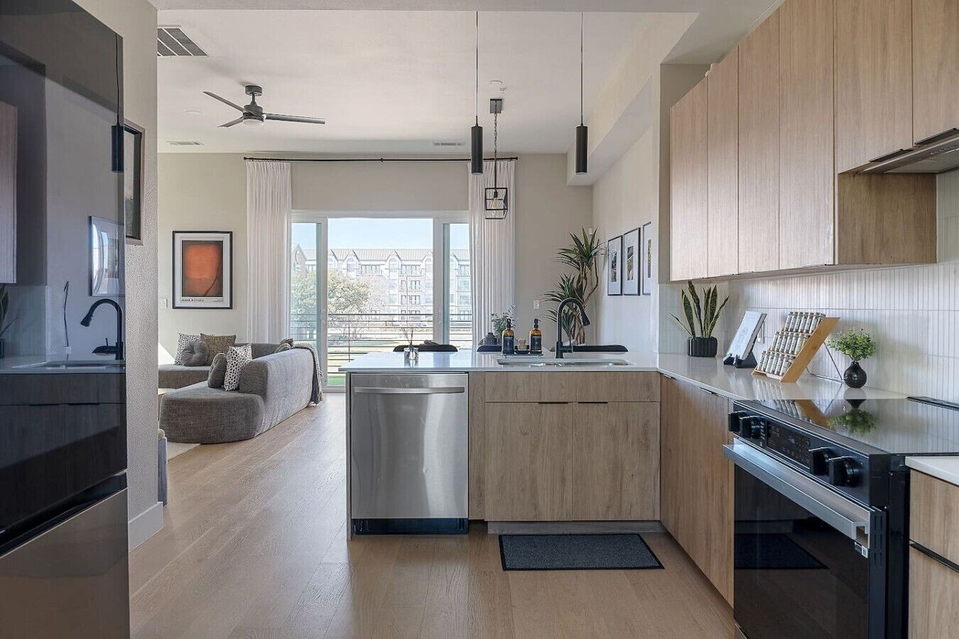 A modern kitchen with a central island, stainless steel appliances, and a view to the outside.