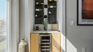 Un meuble à bouteilles, une plante en pot et un tableau encadré accroché au mur.