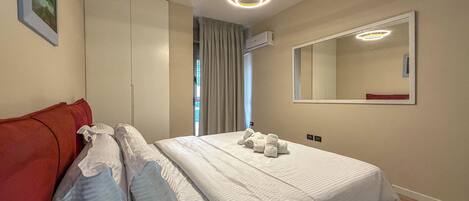 Ett hotellrum med en säng, en röd soffa, en stor spegel och en taklampa.