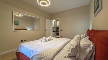 Een hotelkamer met een tweepersoonsbed, een rode hoofdbord, een grote spiegel en een plafondlamp.