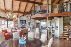 A spacious living area with a dining table, comfortable seating, a kitchen, and a staircase leading to an upper level.