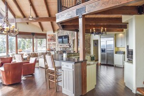 A spacious living area with a large island, wooden beams, and a stone fireplace.