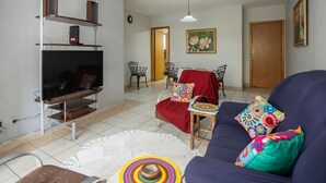 Ein Wohnzimmer mit Fernseher, Sofa und Essbereich.