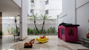 Ein Innenhof mit Spielbereich, einem kleinen rosa Spielhäuschen und einem Spielbagger.