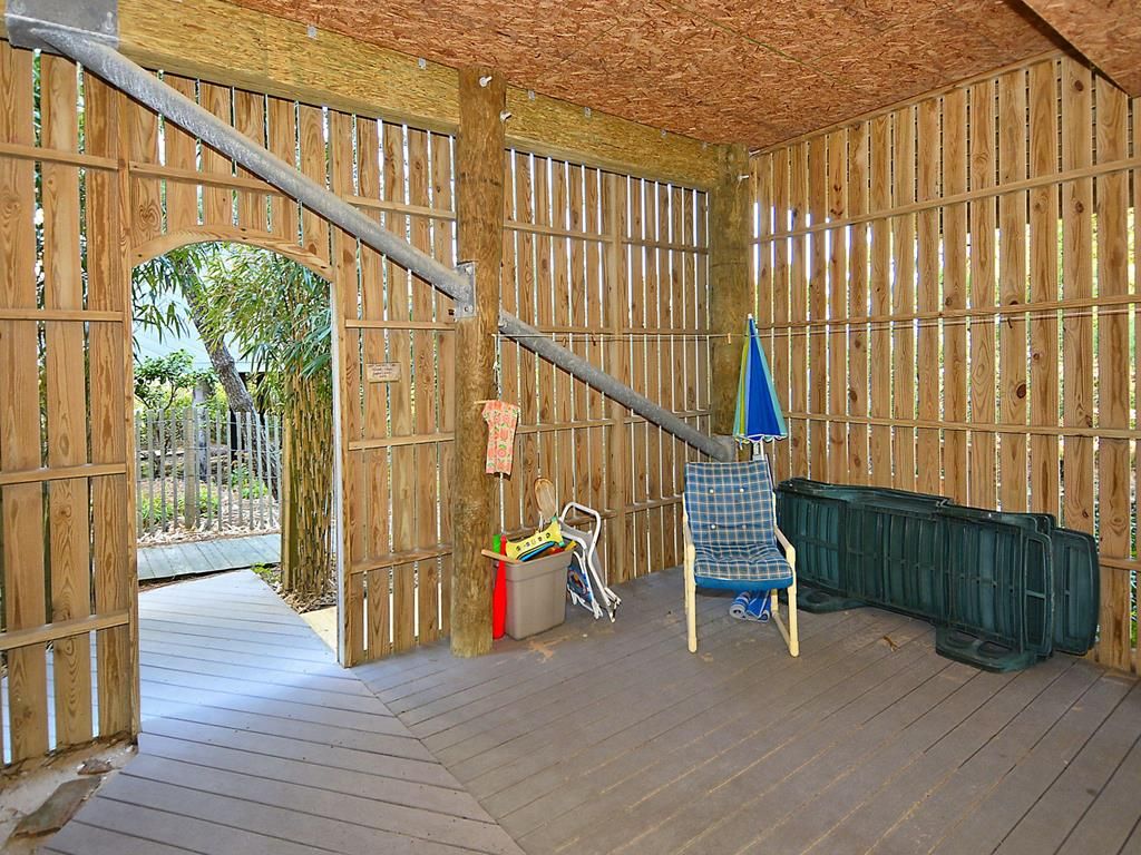 A wooden room with a sloped ceiling, a wooden door, a chair, a table, and a green container.