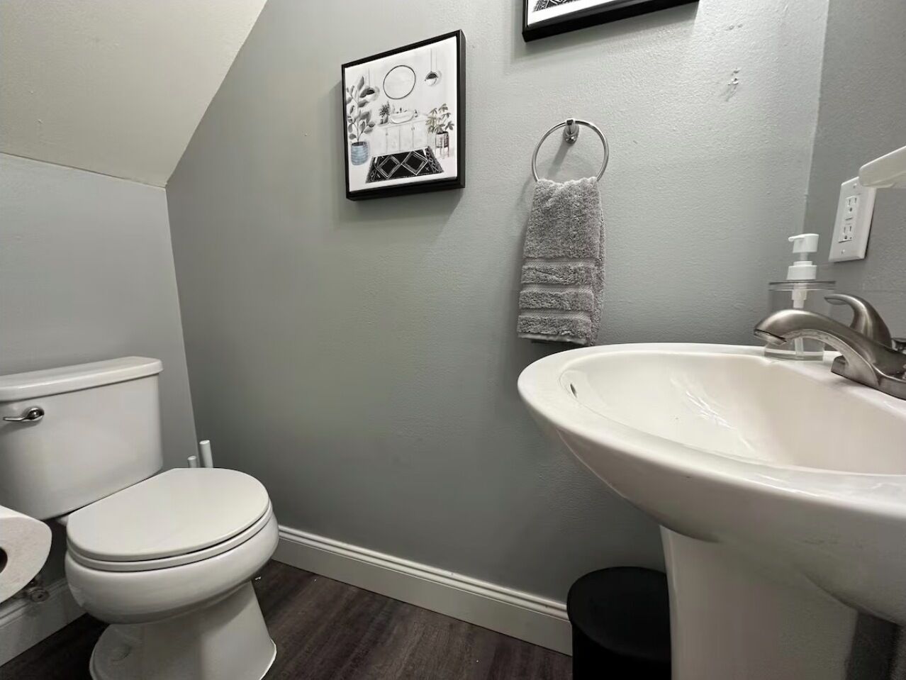 Un baño con inodoro, lavabo y un cuadro en la pared.