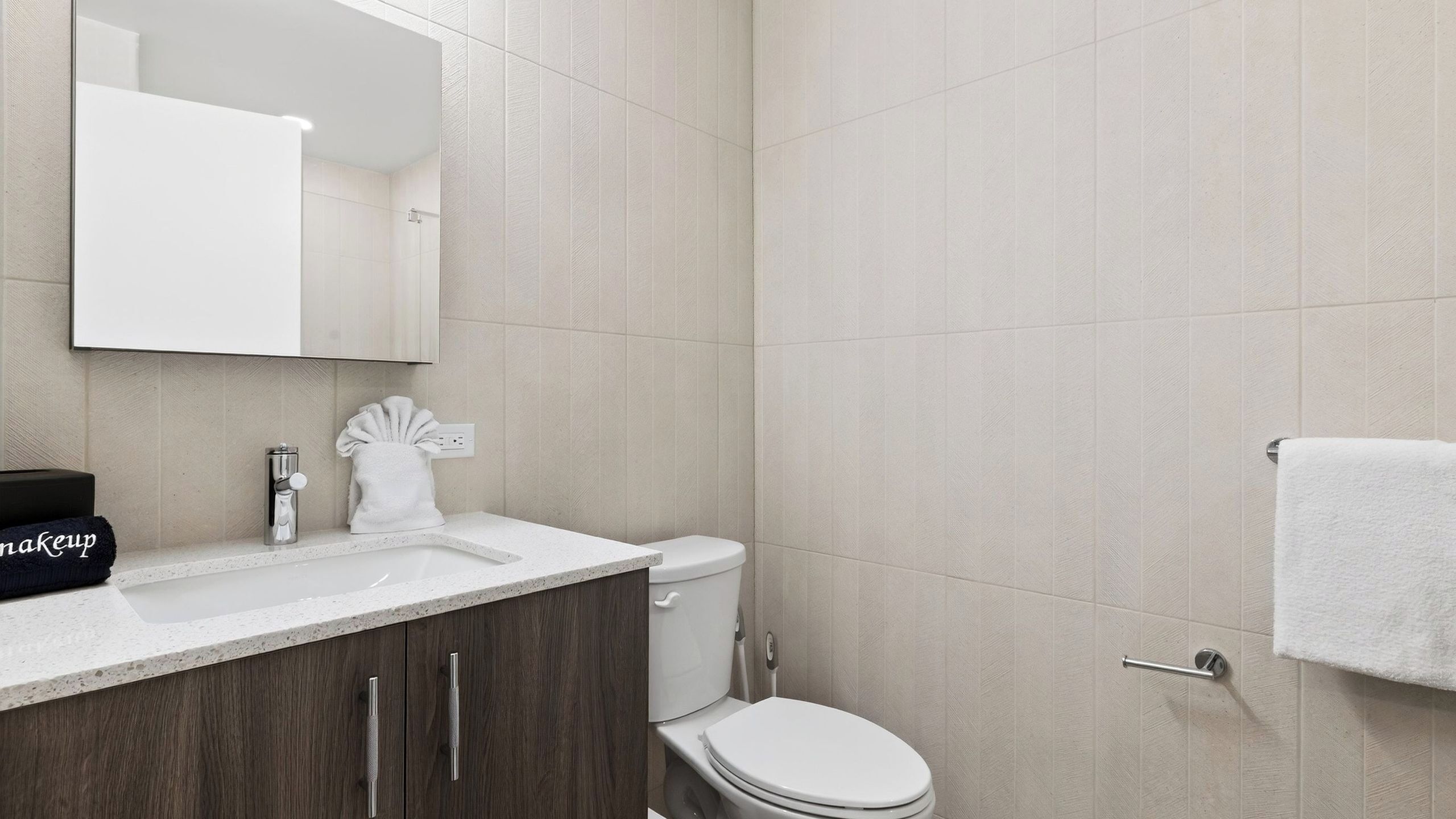 A modern bathroom with a white sink, dark wooden cabinets, a toilet, and a shower area.