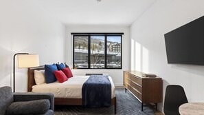 A hotel room with a bed, a desk, a chair, a TV, and a window with a view of buildings. - Pioche Peak by Avantstay Scenic Studio Retreat Spa Access Minutes to Skiing + Main Street (Park City)