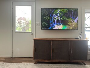 Ein Fernseher an einer Wand oberhalb eines Holzschranks mit Tür.