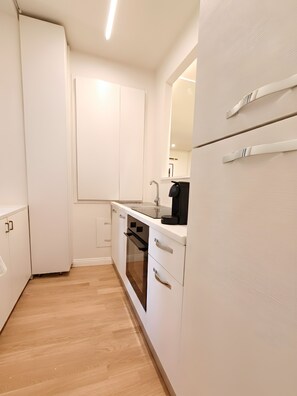 A compact kitchen with white cabinetry, a built-in oven, and a sink. - Milan Porta Venezia Chic Liberty Flat: Wifi, AC & Metro (Milano)