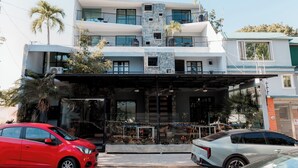 Un immeuble à plusieurs étages doté de balcons, d’une entrée couverte et d’une voiture garée devant.