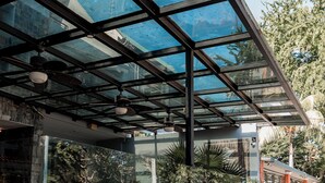 Un espace extérieur moderne, aménagé avec des murs en verre, une table de billard et des plantes en pot.