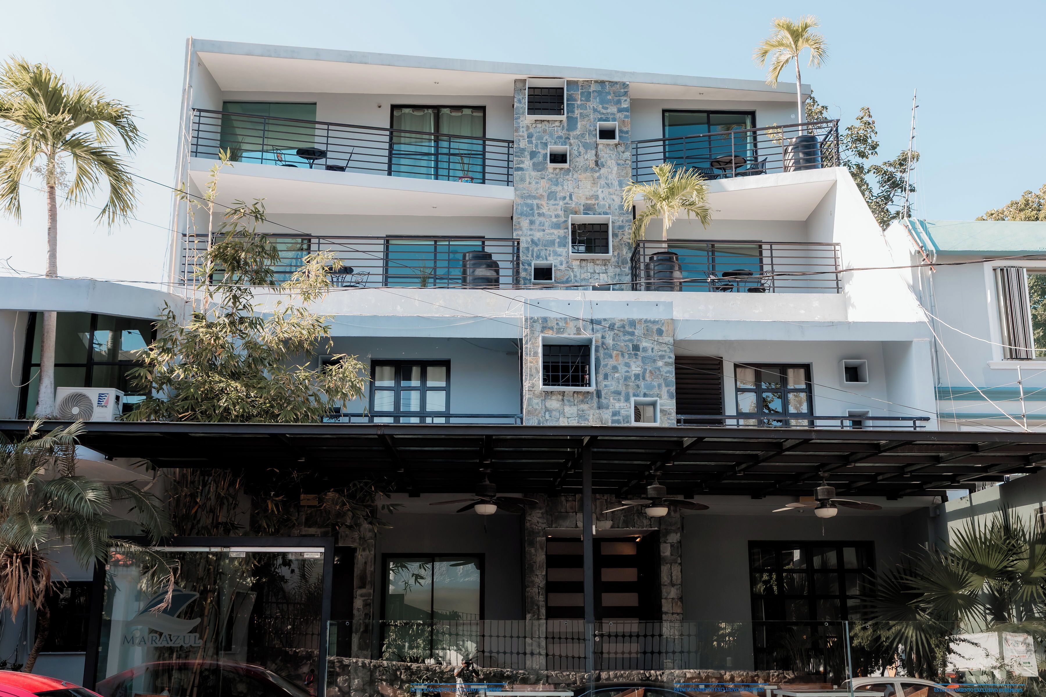 A multi-story building with balconies, large windows, and a covered entrance area.