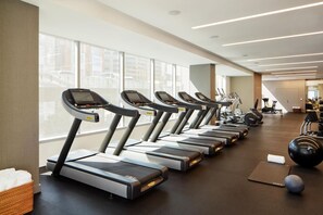 Uma academia com esteiras, bolas de exercício e pesos.