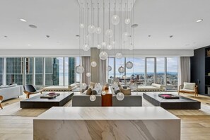A spacious living area with a large window, modern furniture, and hanging spherical light fixtures. - Stylish 2BR Retreat at Spera-Prime Location (San Francisco)