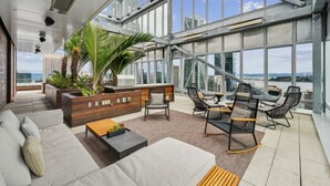 En modern takterrass med en stor glasvägg, utomhusmöbler och utsikt över stadsbilden.