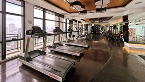 A gym with treadmills, weight machines, and a city view. - Executive Studio w/ Sunset View - Makati CBD (Makati)