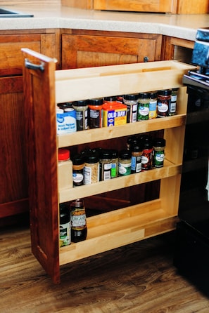 A wooden spice rack with various bottles and containers.