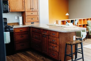 A kitchen with wooden cabinets, a countertop, and a bar stool.