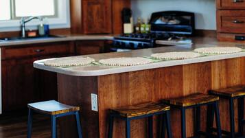 Una cucina con mobili in legno, un forno a microonde, un piano cottura e uno sgabello da bar.