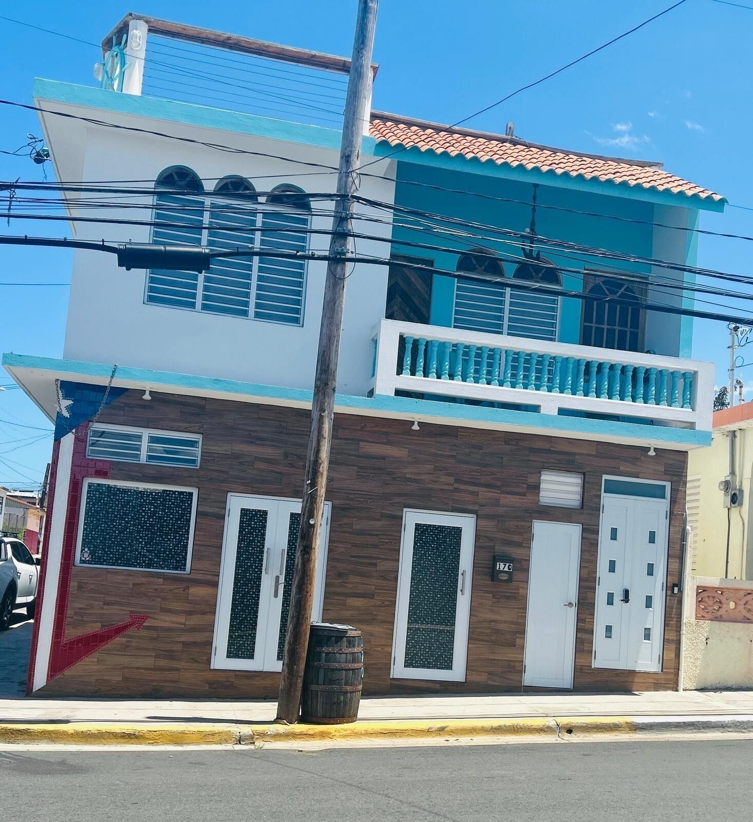 Un bâtiment à deux étages doté d’un balcon, d’une façade en bois et d’une palette de couleurs bleue et blanche.