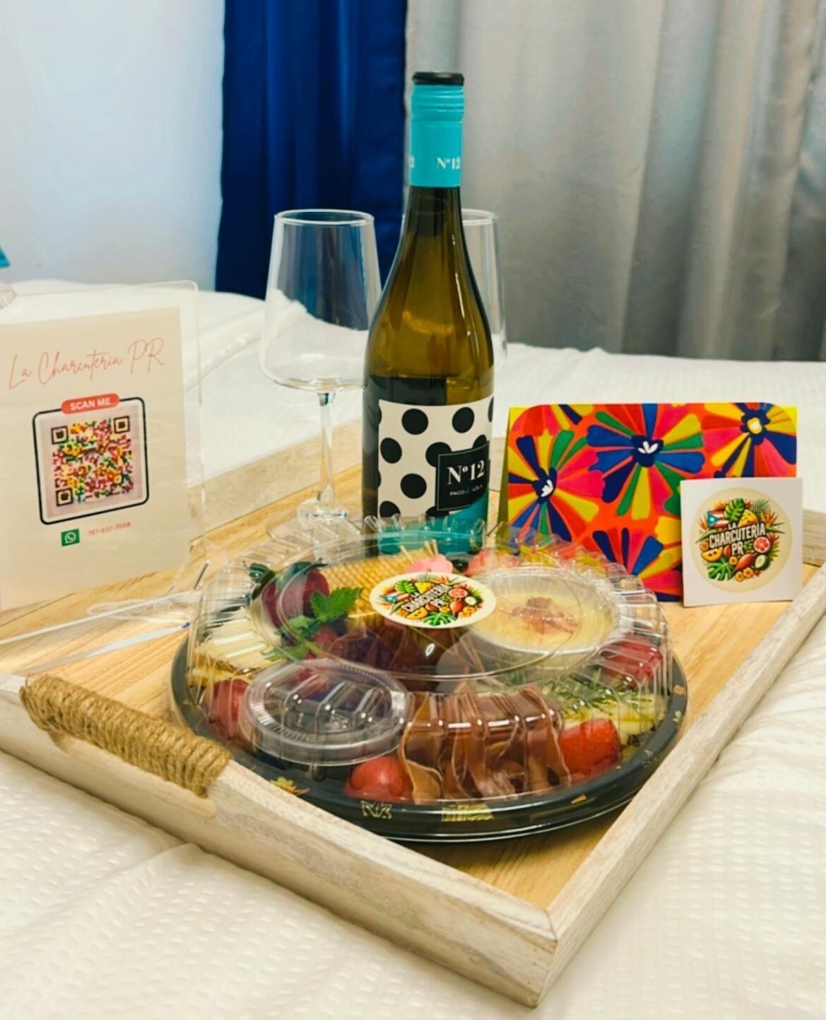 A tray with a bottle of wine, glasses, a colorful card, and a QR code for La Charcuterie PR.