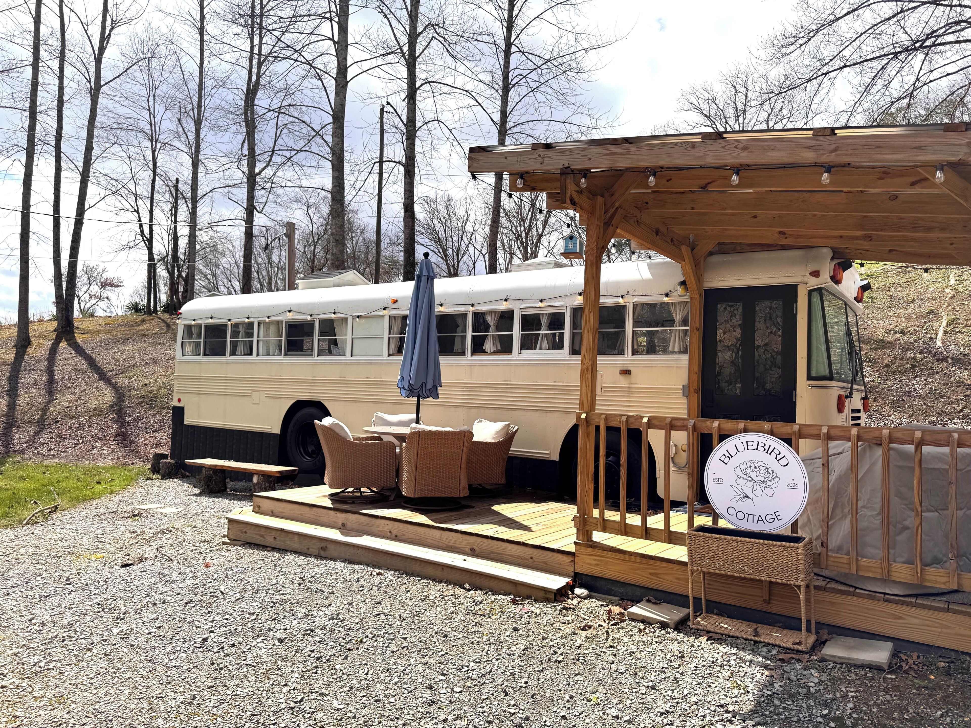 A vintage bus converted into a rustic cabin with outdoor seating and a wooden porch.