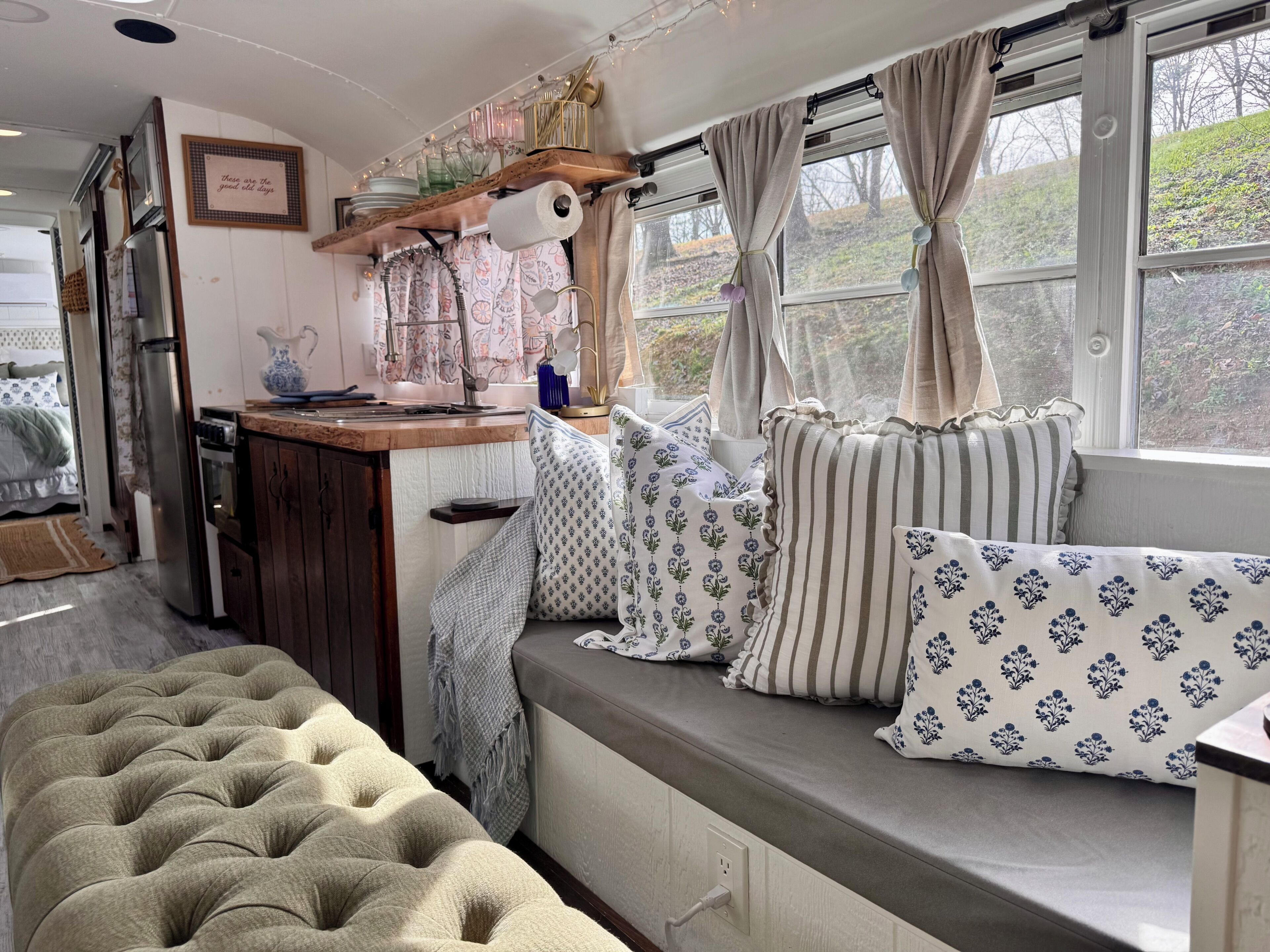 A cozy room with a built-in bench, a kitchen area, and a window with curtains.