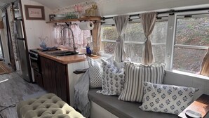 A cozy kitchenette with a stove, sink, and shelves above. - Adorable 1-bedroom studio bus in charming Wears Valley (Sevierville)