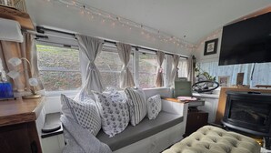 A cozy cabin interior with a sofa, a bench, a fireplace, and a television. - Adorable 1-bedroom studio bus in charming Wears Valley (Sevierville)