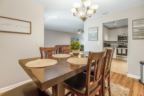 Een eetgedeelte met een houten tafel, geweven placemats en stoelen.