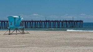 Une plage avec une tour de surveillance pour sauveteurs portant le numéro « 2 » et une jetée qui s’avance dans l’eau.