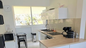 Una cucina moderna con mobili bianchi, un'isola centrale, lavastoviglie integrata e una finestra che offre luce naturale.