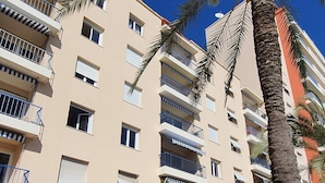 Un hotel a più piani con balconi, una palma e un cartello che riporta la scritta 'La Perle de l'Azur'.