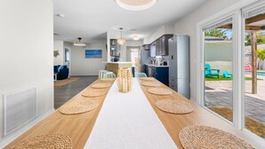Una cucina moderna con isola centrale, una zona pranzo con un tavolo lungo e vista sul patio esterno.