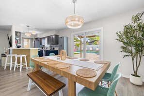 A modern kitchen with a dining area, large windows, and a view of a swimming pool. - Tiki Paradise Resort Heated Saltwater Pool (Largo)