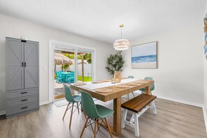 A dining area with a wooden table, green chairs, and a hanging light fixture. - Tiki Paradise Resort Heated Saltwater Pool (Largo)