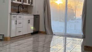 Une cuisine avec des meubles blancs, un robinet noir et un lave-vaisselle.