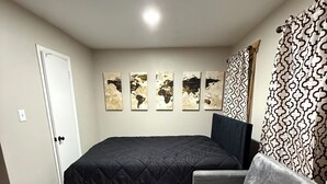 Une chambre à coucher avec un lit, un canapé, une porte et un mur orné de cinq tableaux.