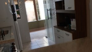 A kitchen with white cabinets, a refrigerator, and a glass door leading to a balcony. - Prado, Where it all began (Prado)