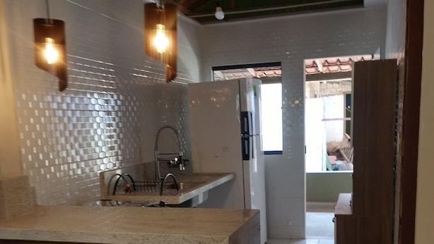 A kitchen with a central island, bar stools, a sink, and a refrigerator. - Prado, Where it all began (Prado)