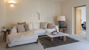 A modern living room with a sofa, a coffee table, a lamp, and a ceiling fan. - Yema House - Naoussa Bay (4666+369 Protorgia, Greece)